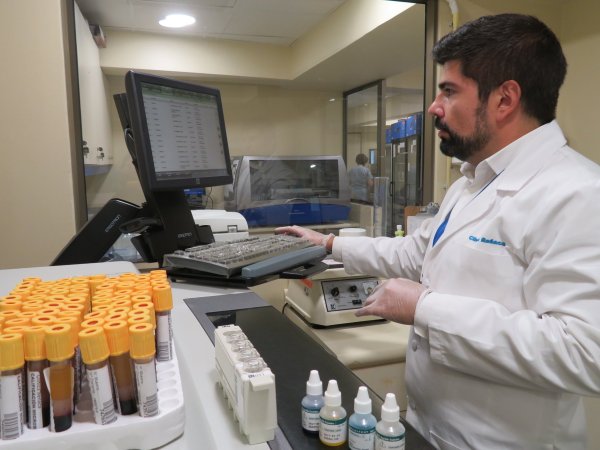 Un especialista de laboratorio opera una computadora, dedicándose a su labor en el laboratorio y análisis de muestras.
